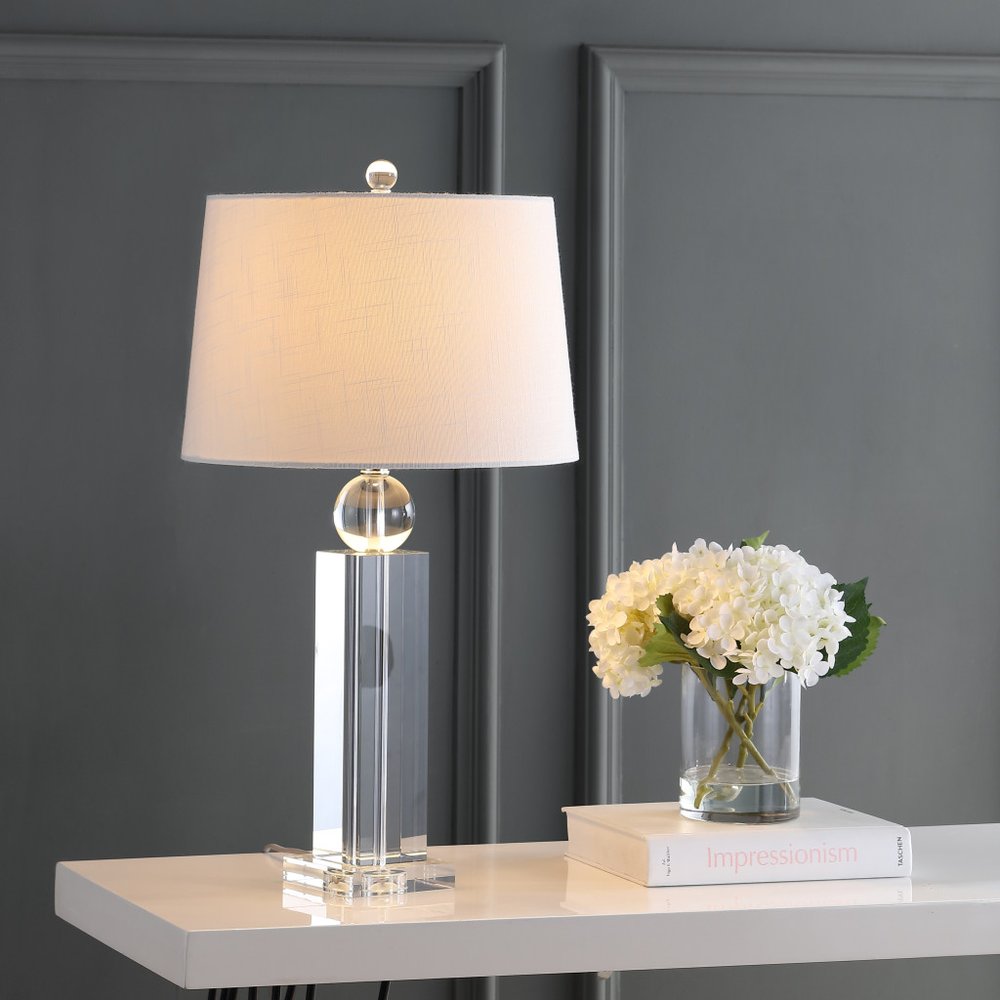 29" Silver And Clear Table Lamp With Empire Shade displayed on a tabletop in a furnished interior against a dark wall.