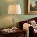 29" Silver And Clear Table Lamp With Empire Shade displayed on a tabletop in a furnished interior against a tan wall.