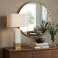 29" Gold Novelty Table Lamp With Shade displayed on a dark wood tabletop in a furnished interior against a tan wall.
