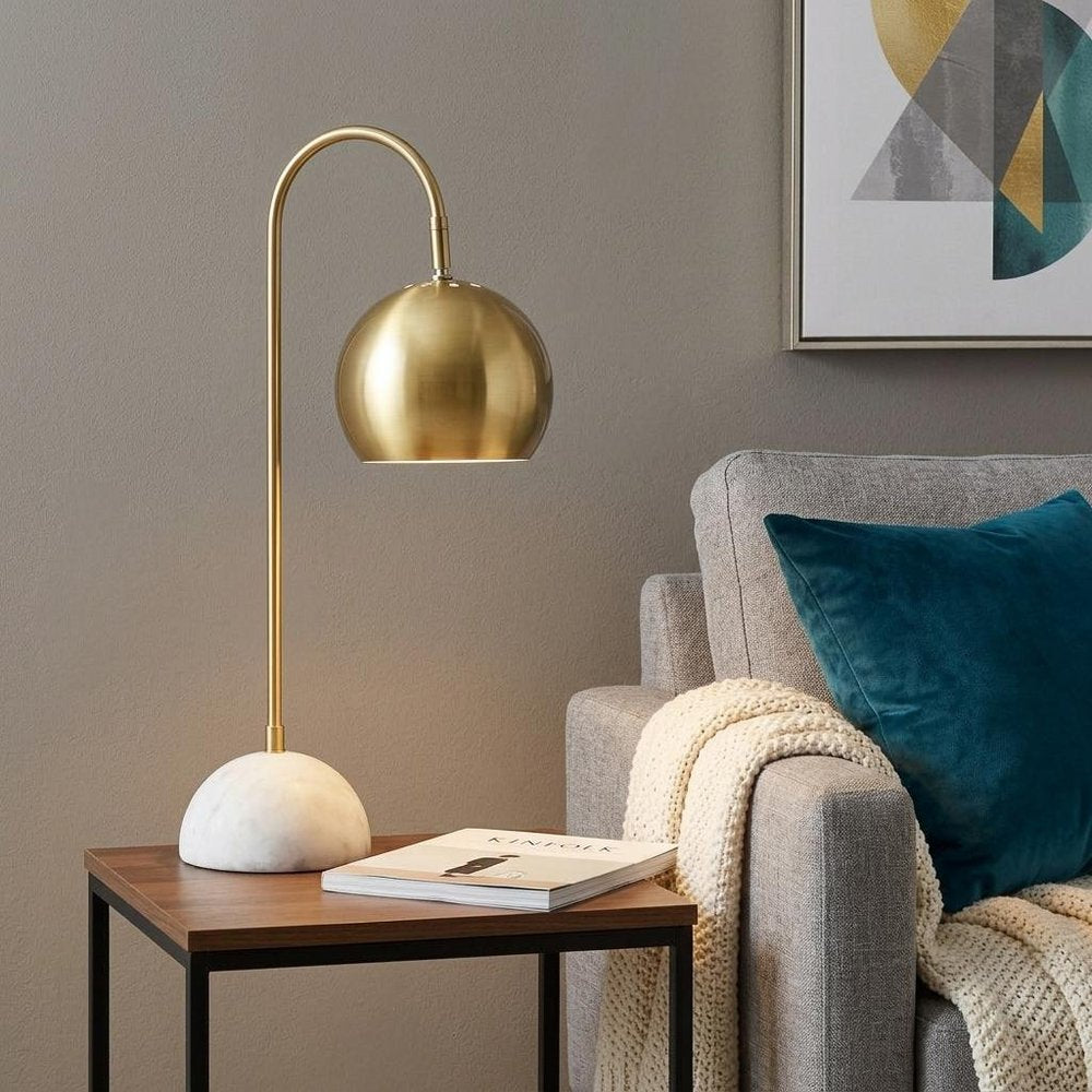 24" White Novelty Table Lamp With Globe Shade displayed on a wood tabletop in a furnished interior against a gray wall.