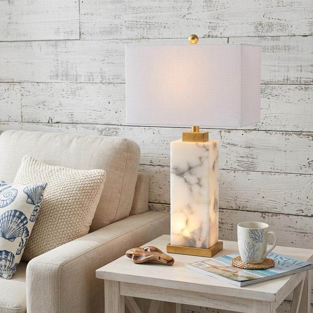 28" Gold Novelty Table Lamp With Shade displayed on a wood tabletop in a furnished interior against a light gray wall.