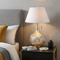 31" Gold Novelty Table Lamp With Globe Shade displayed on a tabletop in a furnished interior against a light gray wall.