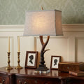30" Brown And Clear Novelty Table Lamp With Shade displayed on a tabletop in a furnished interior against a gold wall.
