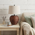 25" Clear Urn Table Lamp With Globe Shade displayed on a dark wood tabletop in a furnished interior against an off-white wall.