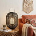 27" Black Novelty Lantern styled in a furnished interior with an off-white wall on a dark wood floor.