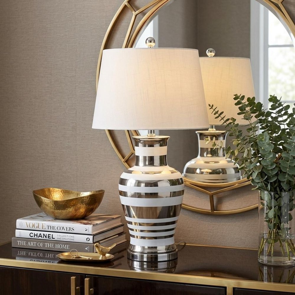 29" Silver Urn Table Lamp With Empire Shade displayed on a tabletop in a furnished interior against a tan wall.