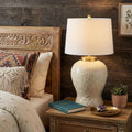 32" Clear Novelty Table Lamp With Empire Shade displayed on a dark wood tabletop in a furnished interior against a dark brown wall.