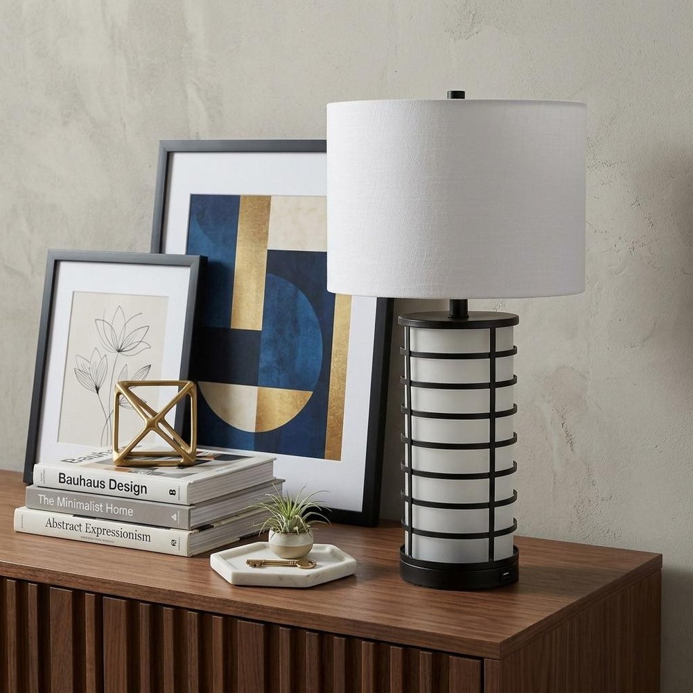 27" Black USB Table Lamp With Drum Shade displayed on a dark wood tabletop in a furnished interior against a light gray wall.