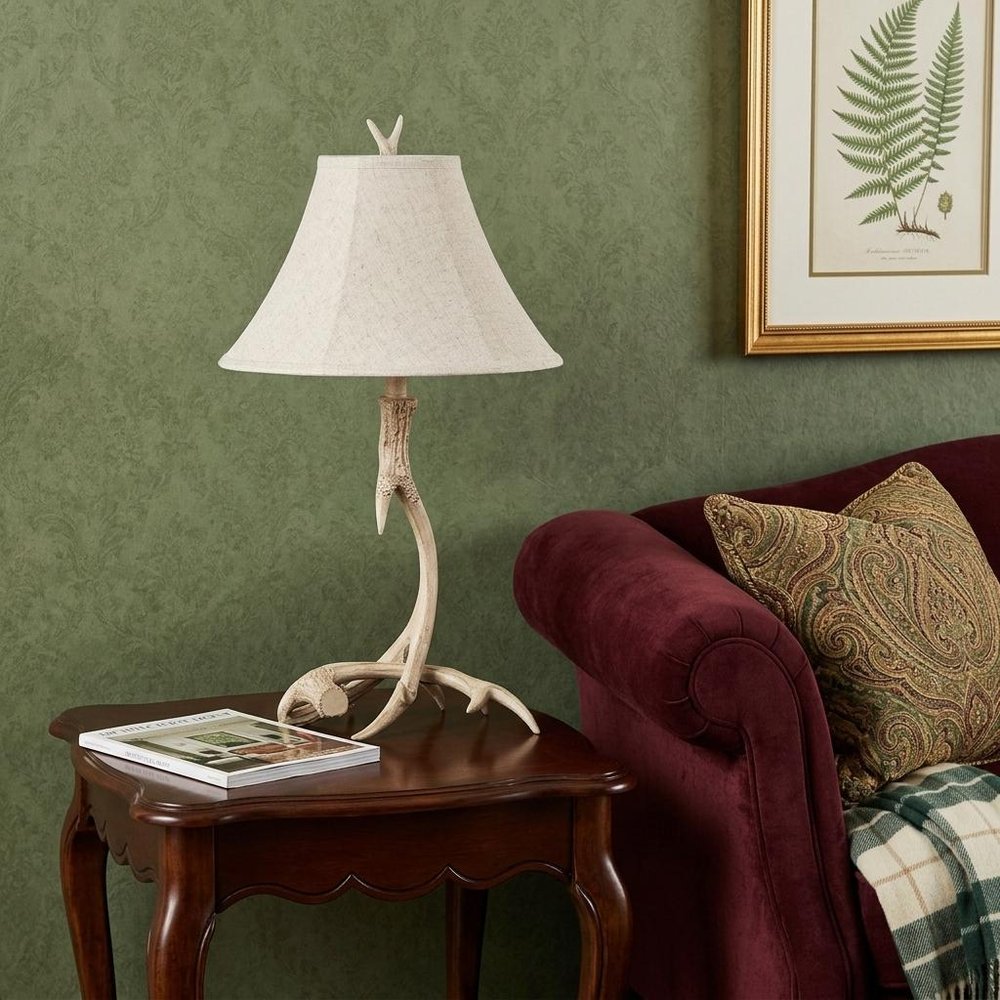 28" Beige Antlers Table Lamp With Bell Shade displayed on a tabletop in a furnished interior against a olive wall.