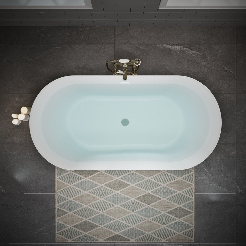 Top view of a white acrylic oval bathtub filled with water, set on a dark tiled floor with a diamond-patterned rug.