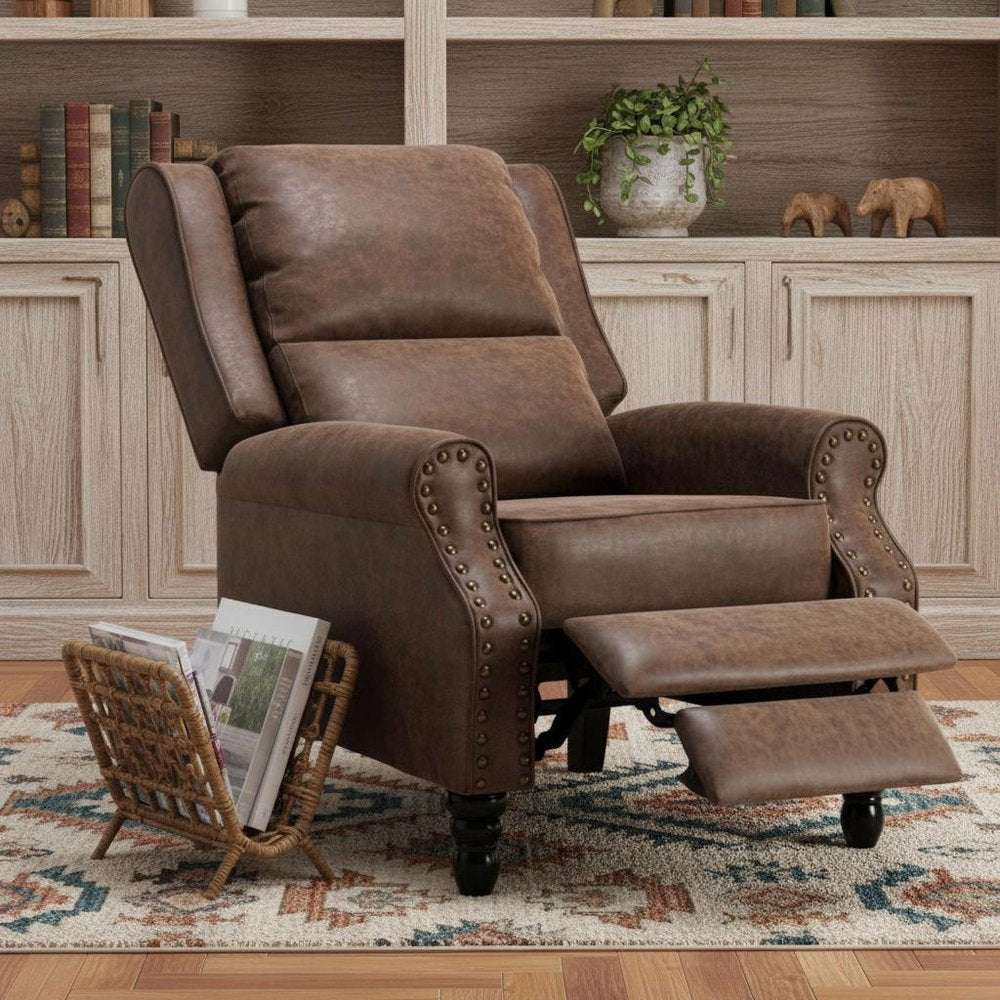 Brown faux leather manual recliner with nailhead trim and extended footrest in a room with bookshelves and a rug.