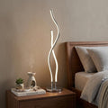 26" Silver Novelty Table Lamp displayed on a dark wood tabletop in a furnished interior against a tan wall.