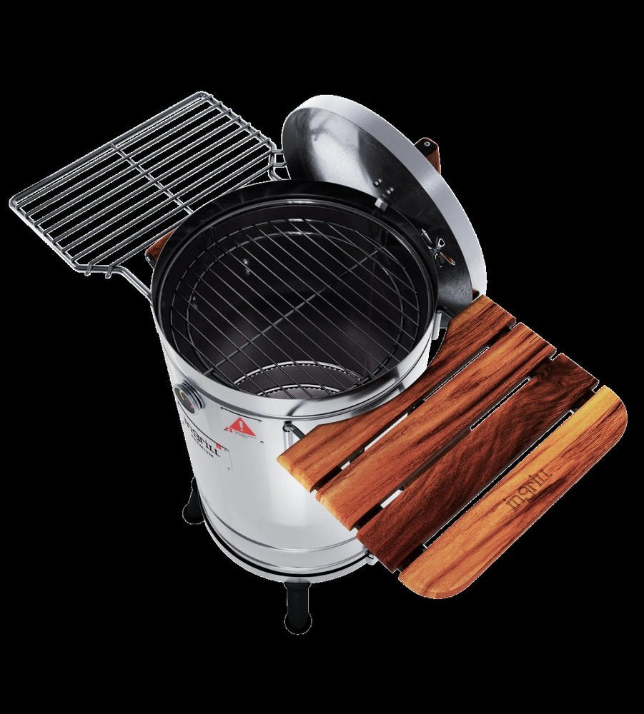 Silver stainless steel portable smoker barrel with wooden side table and grill rack against a black background.