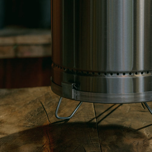 Silver stainless steel portable smoker barrel on a wooden surface.