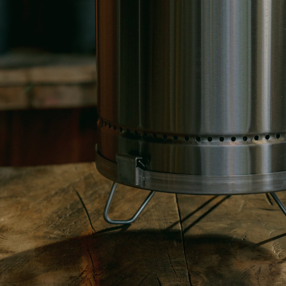Silver stainless steel portable smoker barrel on a wooden surface.