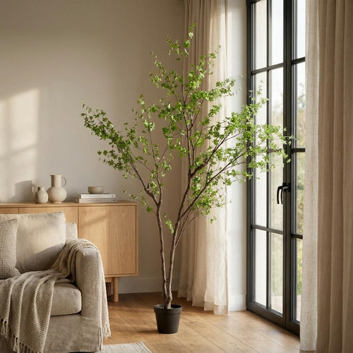 A tall, 118-inch green artificial tree in a cylindrical black pot stands in a living room next to a window and a sofa.