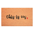 Brown and black "this is us" outdoor coir doormat with a red heart accent.