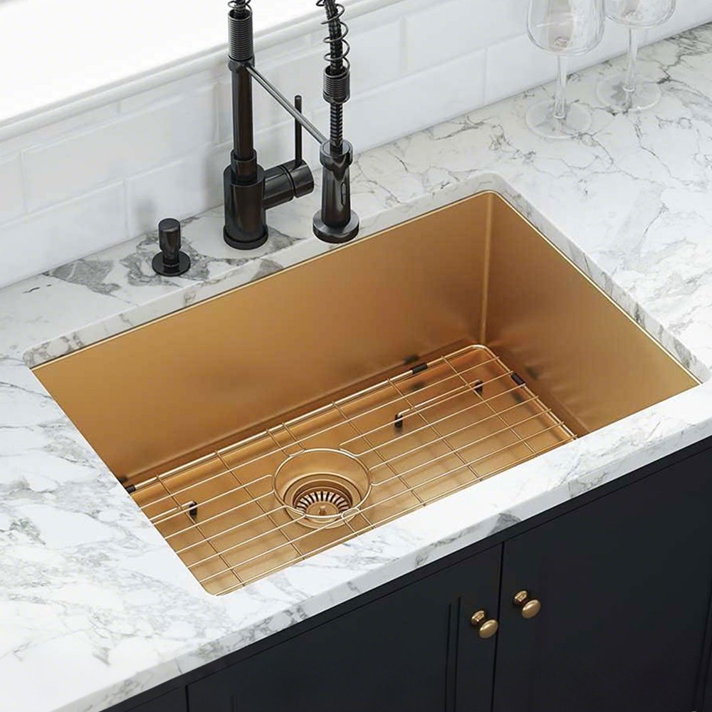 Gold stainless steel undermount kitchen sink with a grid drain and black faucet on a marble countertop.