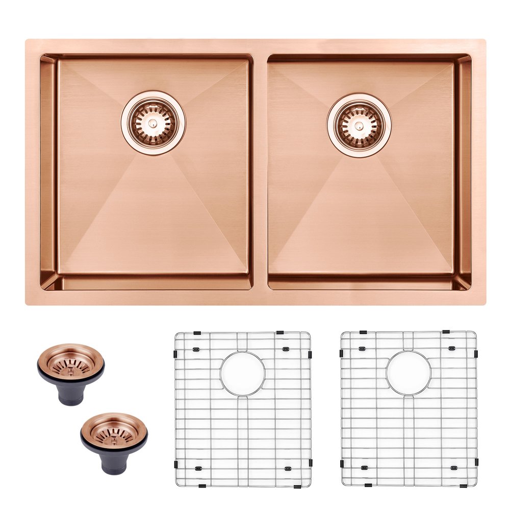 Copper double basin undermount sink with two strainers and two sink grids on a white background.