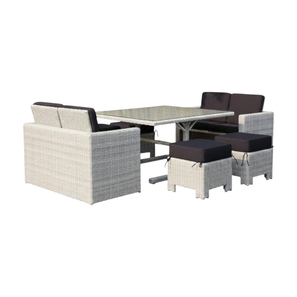 White wicker outdoor patio set with dark gray upholstered cushions, including a table, sofa, and two ottomans.