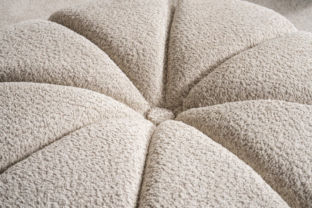Close-up of a taupe tufted boucle ottoman with a textured, plush finish.