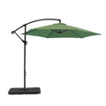 9.5' Green Polyester Hexagonal Cantilever Patio Umbrella with Stand on a white background