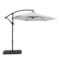 9.5' White Polyester Hexagonal Cantilever Patio Umbrella with Stand on a white background