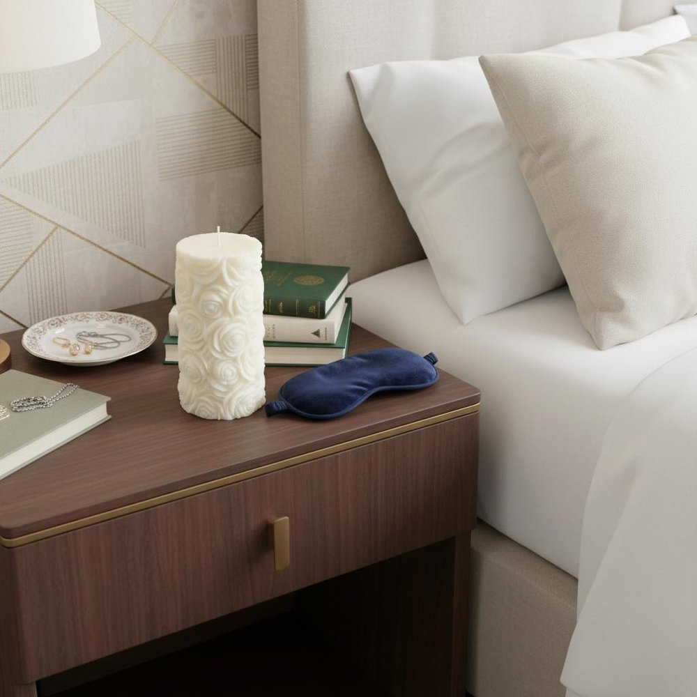 2" Ivory Day at the Spa Scented Candle Cylinder Pillar displayed on a tabletop in a furnished interior against an off-white wall.