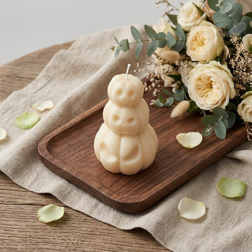 Ivory unscented dimensional pumpkin candle on a wooden tray with a bouquet of cream roses and eucalyptus.