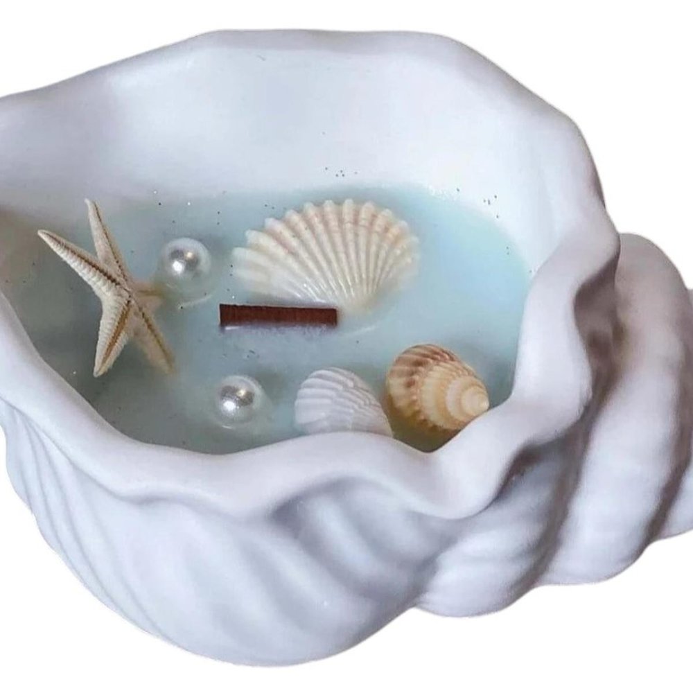 6" Light Blue Unscented Soy Wax Candle In White Resin Novelty Holder With Seashells. Candle isolated on a plain white background, showing a white resin surface.