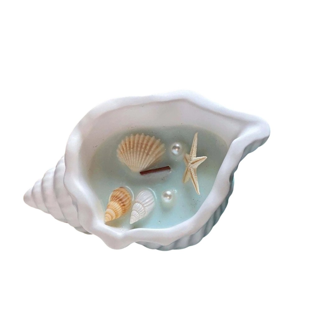 A white resin seashell candle holder with light blue wax, shells, pearls, and a starfish.