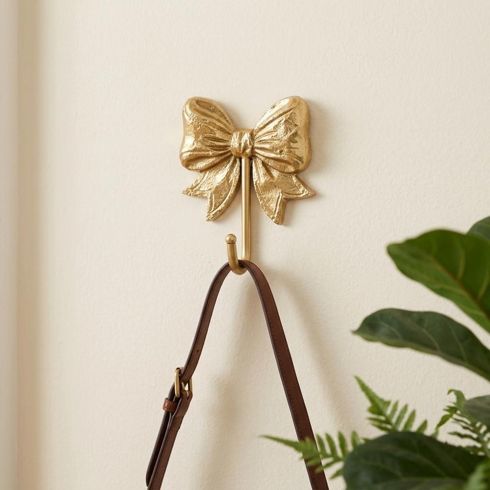 4" Gold Cast Iron Bow Wall Hook styled in a furnished interior with an off-white wall on a tiled floor.