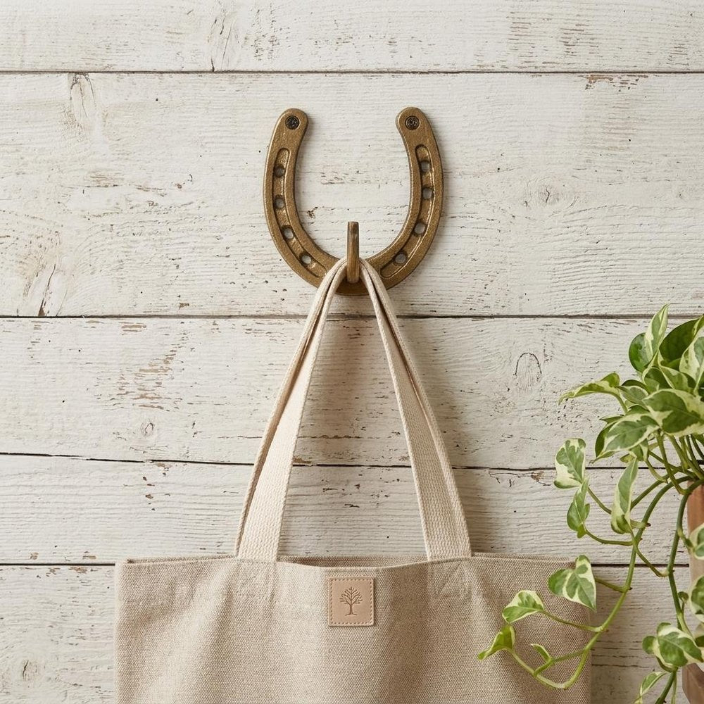 4" Antiqued Gold Cast Iron Horseshoe Wall Hook styled in a furnished interior with an off-white wall on a wood floor.