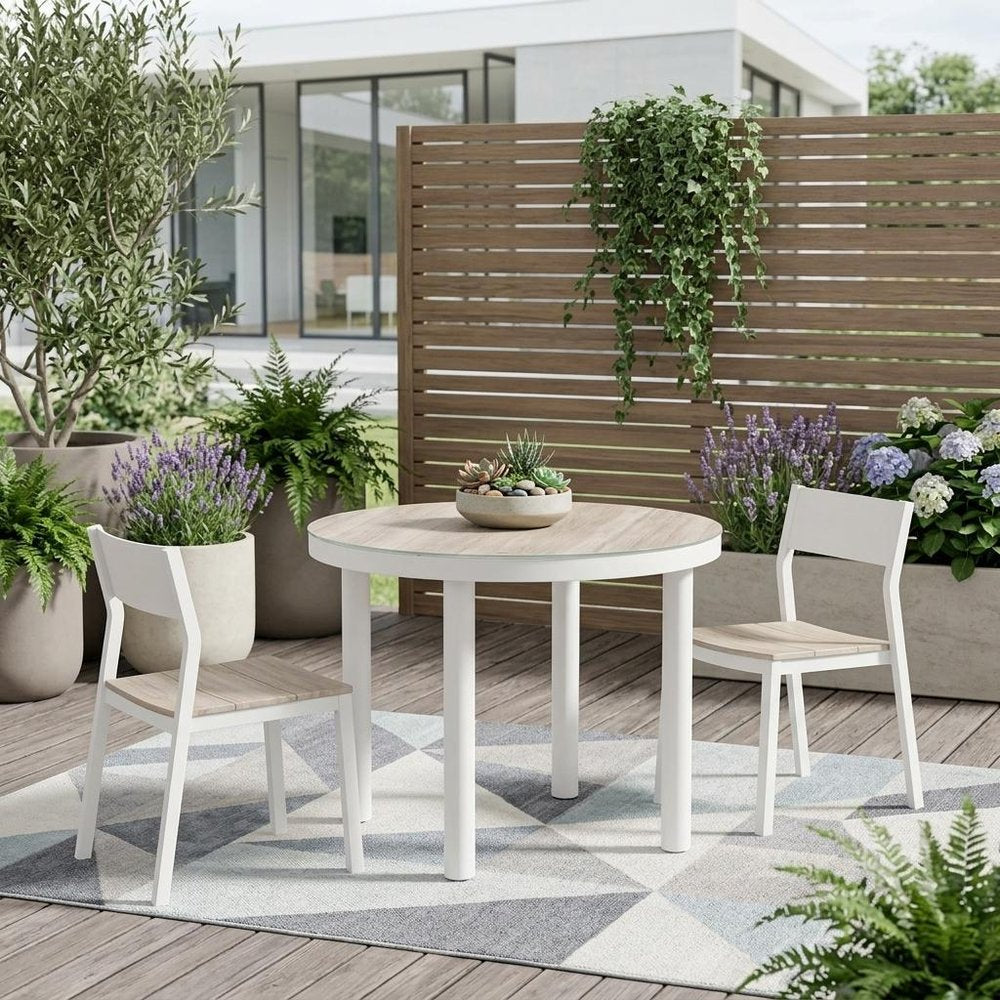 36" Natural and White Glass Wood and Aluminum Round Outdoor Dining Table shown outdoors on a tiled patio with greenery.