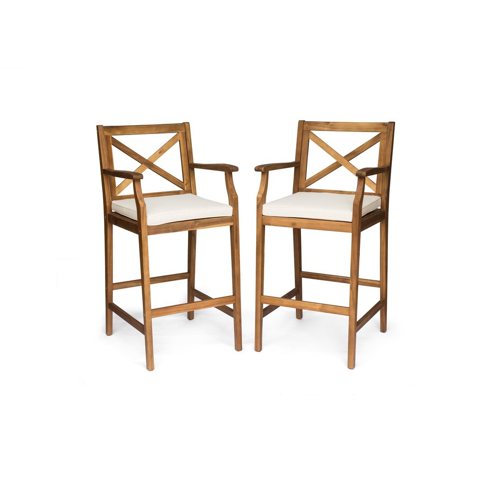 Two brown solid wood outdoor bar height chairs with white cushions on a white background.