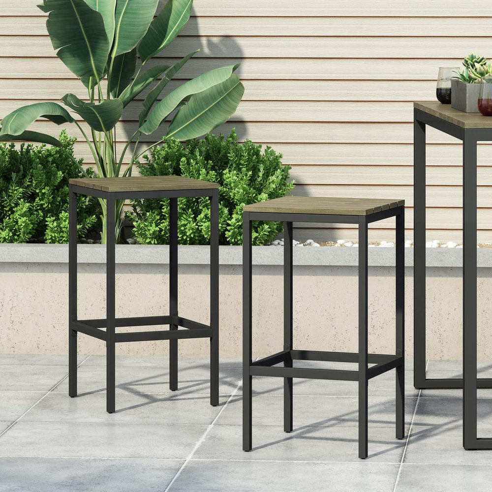 Two gray backless outdoor bar stools with wooden seats and black metal frames on a patio.