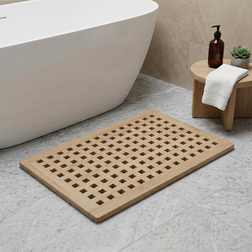 Beige gray teak checkered non-slip bath mat on a marble floor next to a white bathtub.