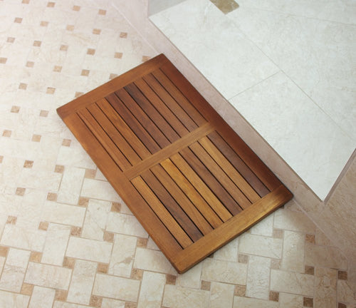 Natural teak bath mat with slatted surface on a tiled floor next to a shower.
