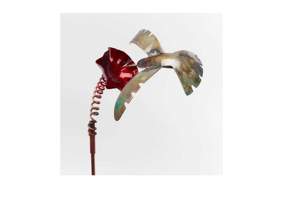Metal garden stake with a red flower and a copper bird in flight against a white background.