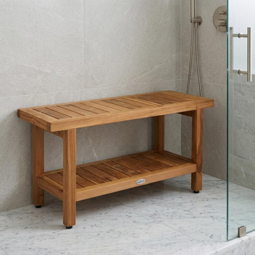 Brown teak shower bench with shelf against gray tiled wall and marble floor in a shower stall.