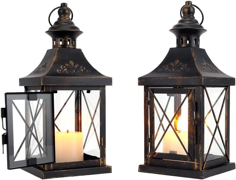 Two black and clear distressed metal and glass tabletop lantern candle holders with lit candles on a white background.
