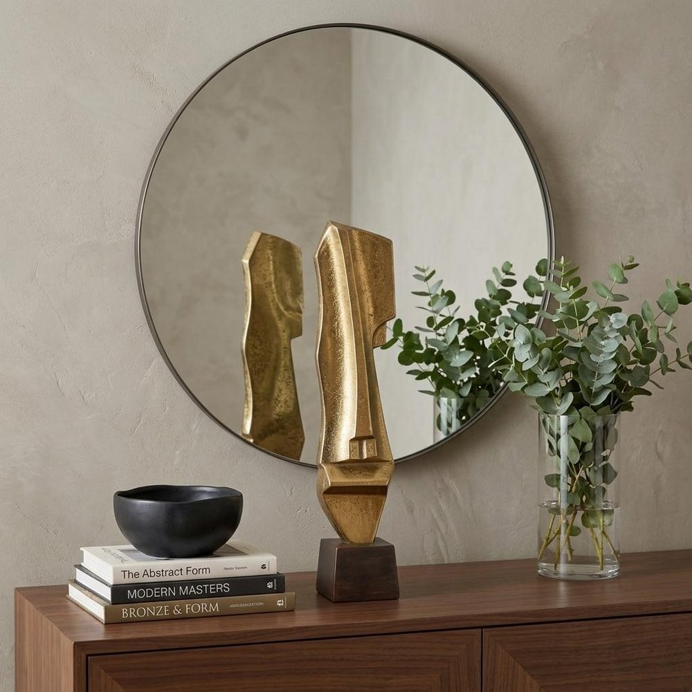 21" Gold And Bronze Aluminum Hand Painted Statue styled in a furnished interior with a tan wall on a dark wood floor.