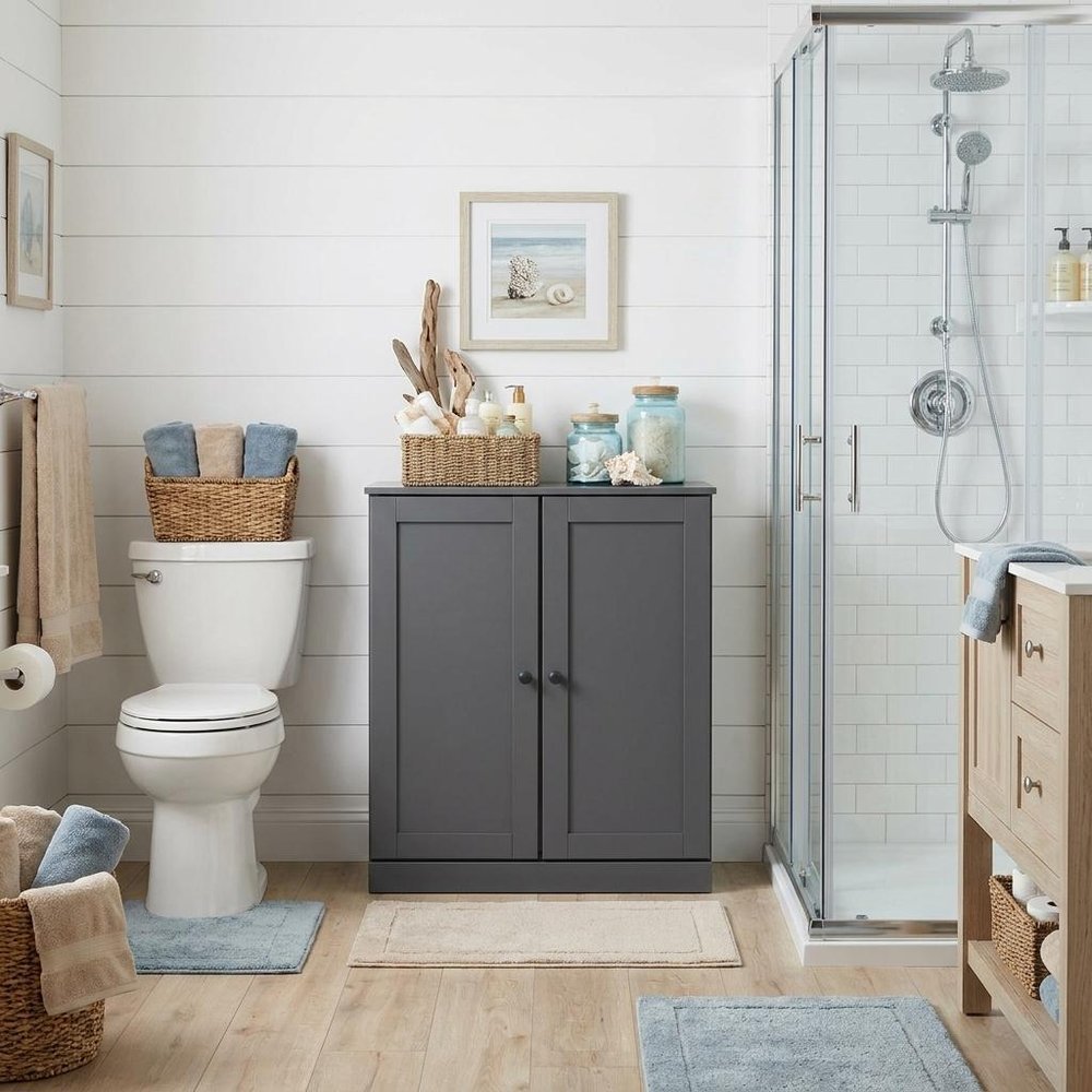 32" White Solid Wood Shaker Style Double Door Linen Cabinet styled in a furnished interior with an off-white wall on a wood floor.