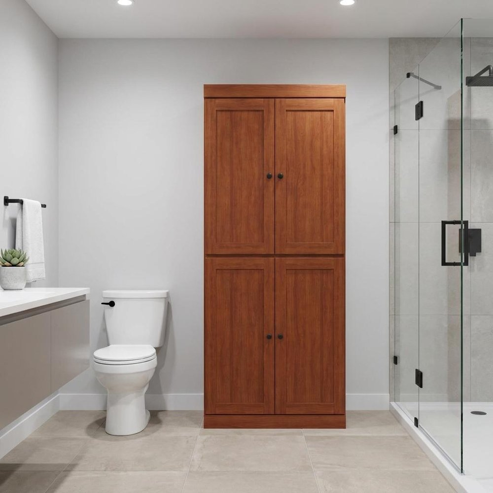 32" Coffee Solid Wood Free Standing Four Door Linen Cabinet styled in a furnished interior with a light gray wall on a wood floor in light gray wood.