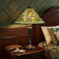 24" Bronze Flowers Two Light Round Tiffany Lamp With Dome Shade styled in a furnished interior with a olive wall on a black floor.