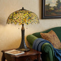 29" Bronze Abstract Two Light Round Tiffany Lamp With Dome Shade styled in a furnished interior with a tan wall on a black floor.