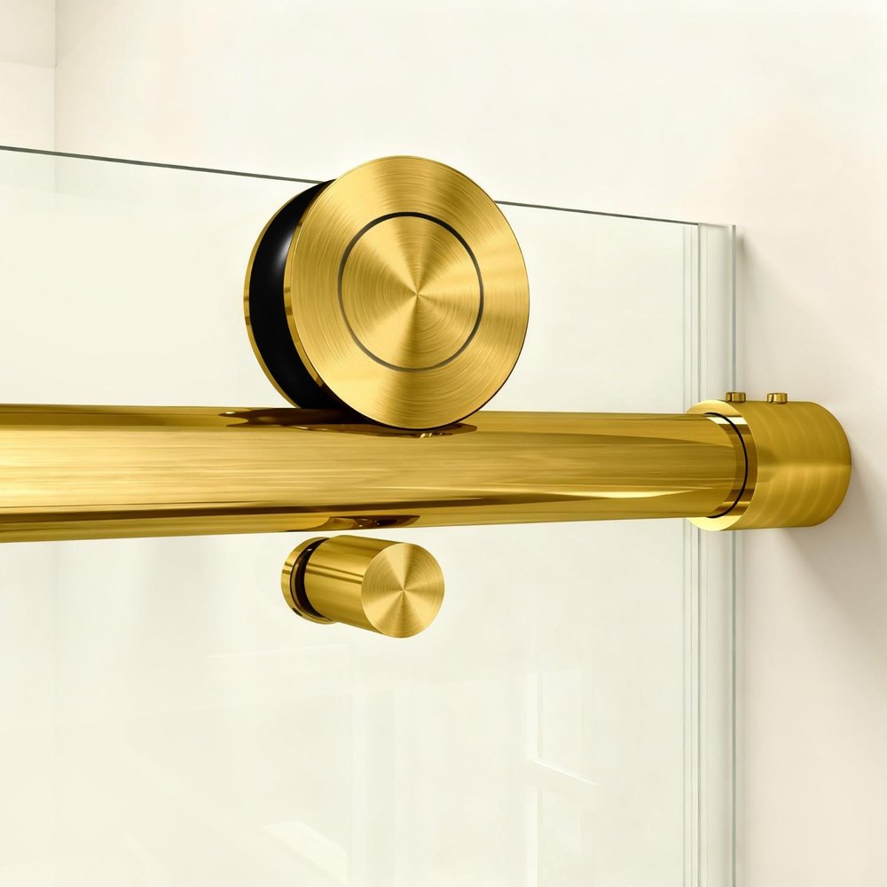 Close-up of a polished brass sliding shower door hardware with a roller wheel on a glass panel.