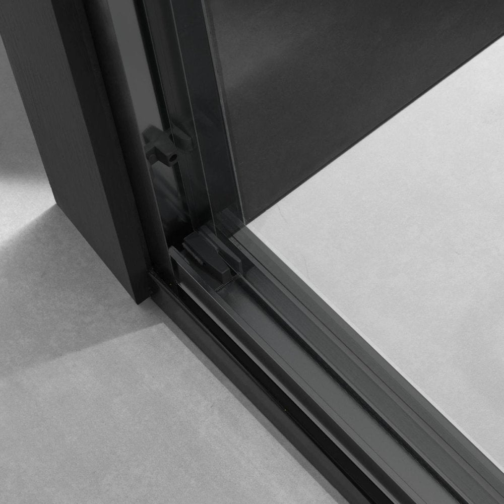 Close-up of a black framed glass shower door with a gray tiled floor.