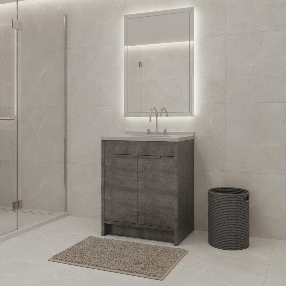 Gray wood freestanding bathroom vanity with white sink and illuminated mirror in a tiled bathroom.